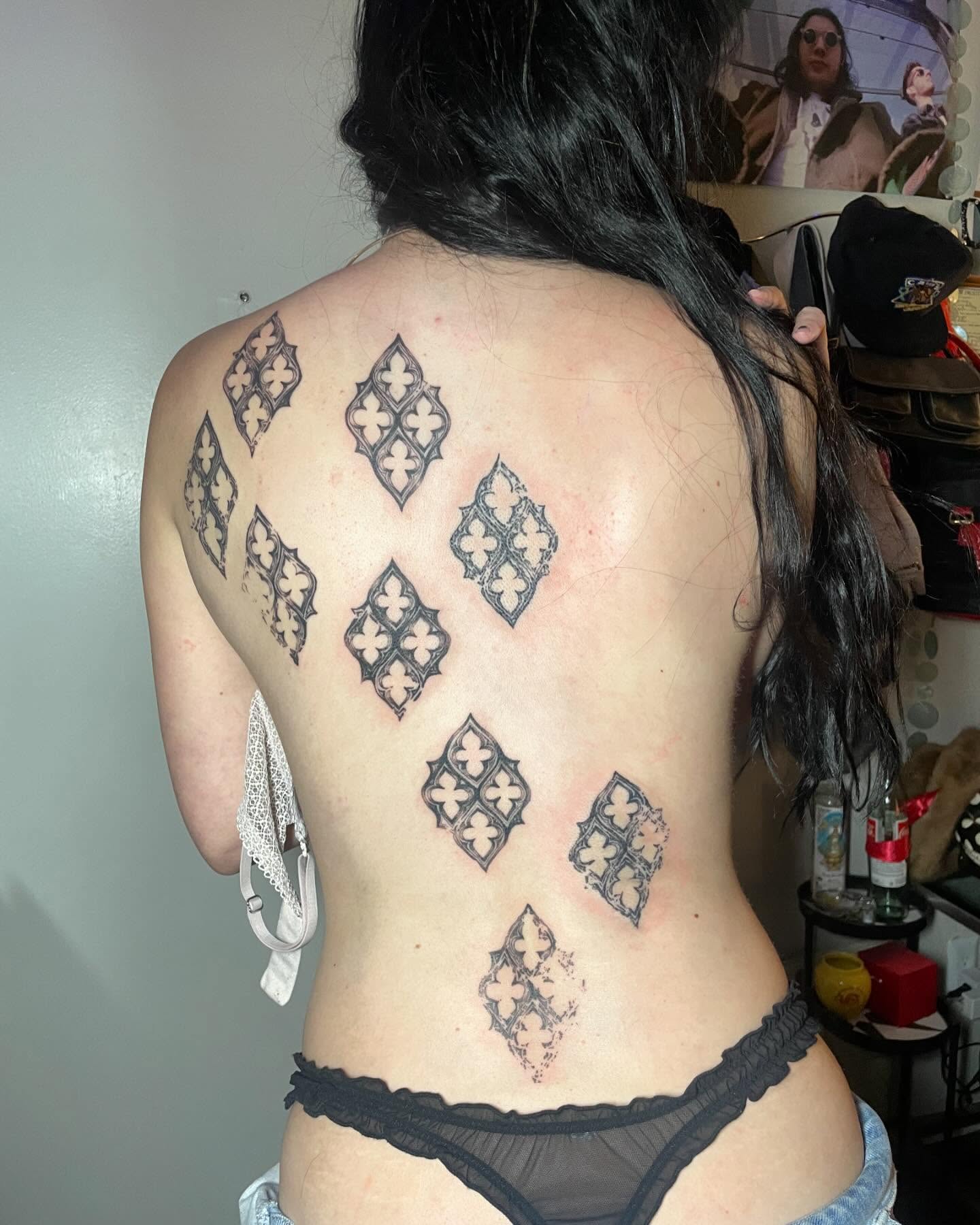 Repeating ornamental diamond tattoos running down a client's spine