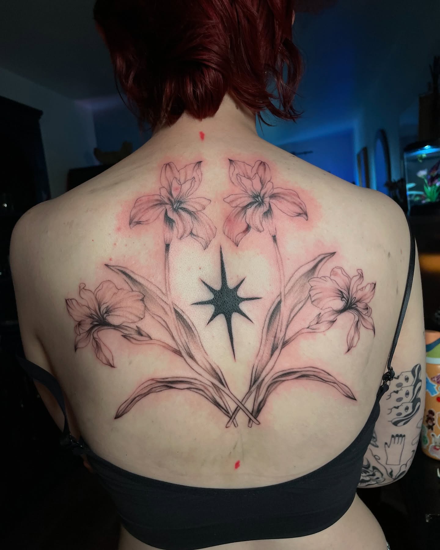 Pink botanical back tattoo arranged around a black star