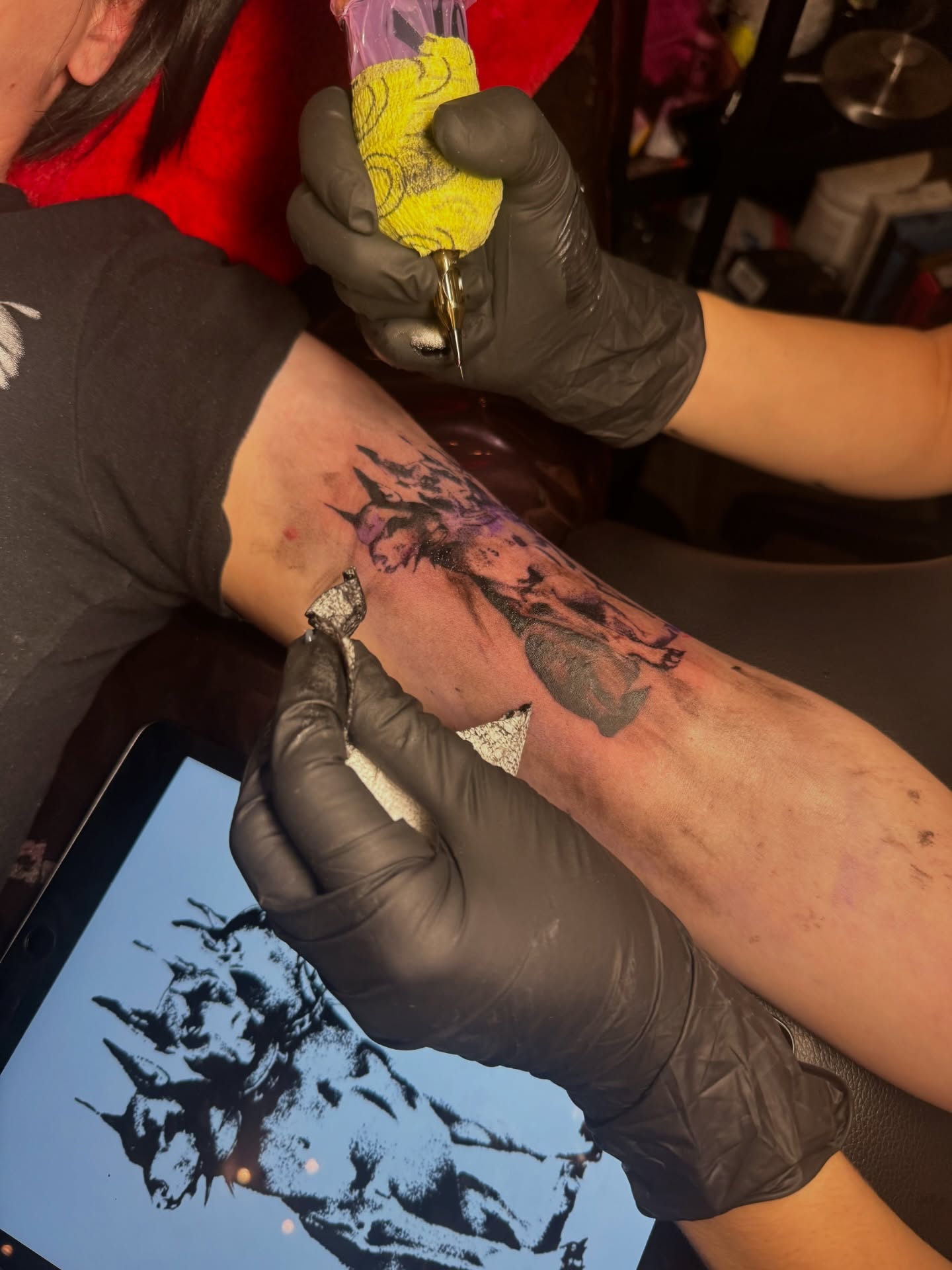 Tattoo artist working on a dark illustrative portrait tattoo