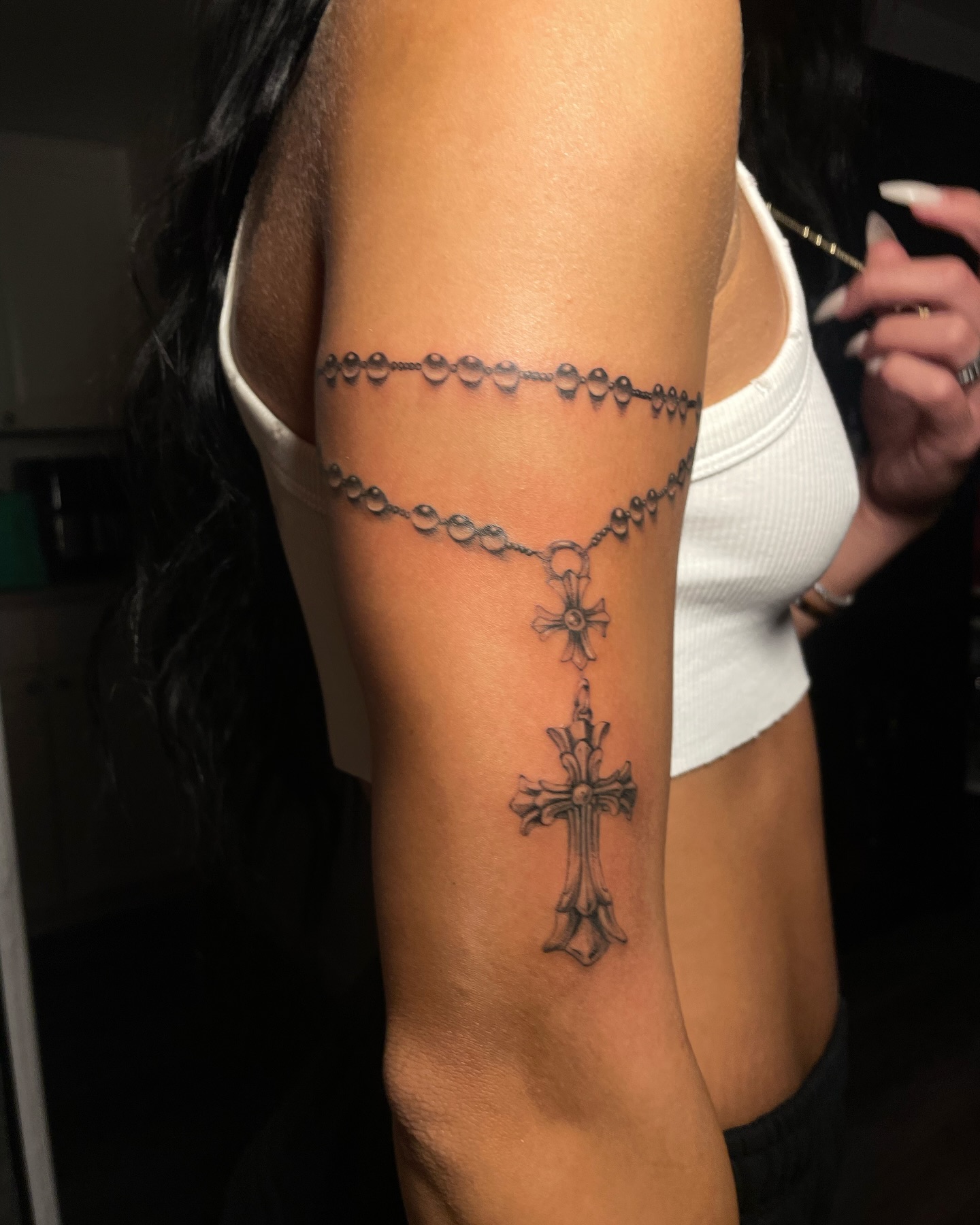 Fine-line rosary armlet tattoo with hanging cross