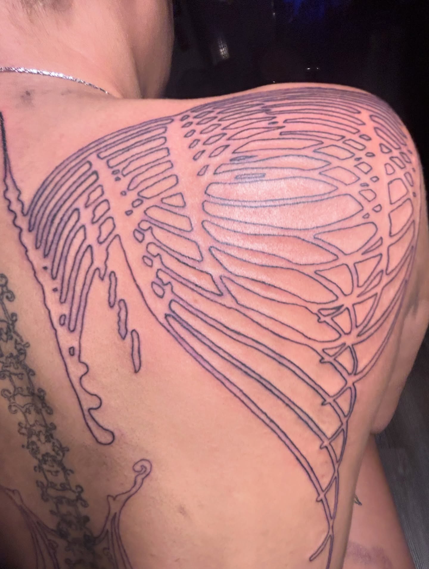 Large anatomical rib-cage tattoo outline across a client's side